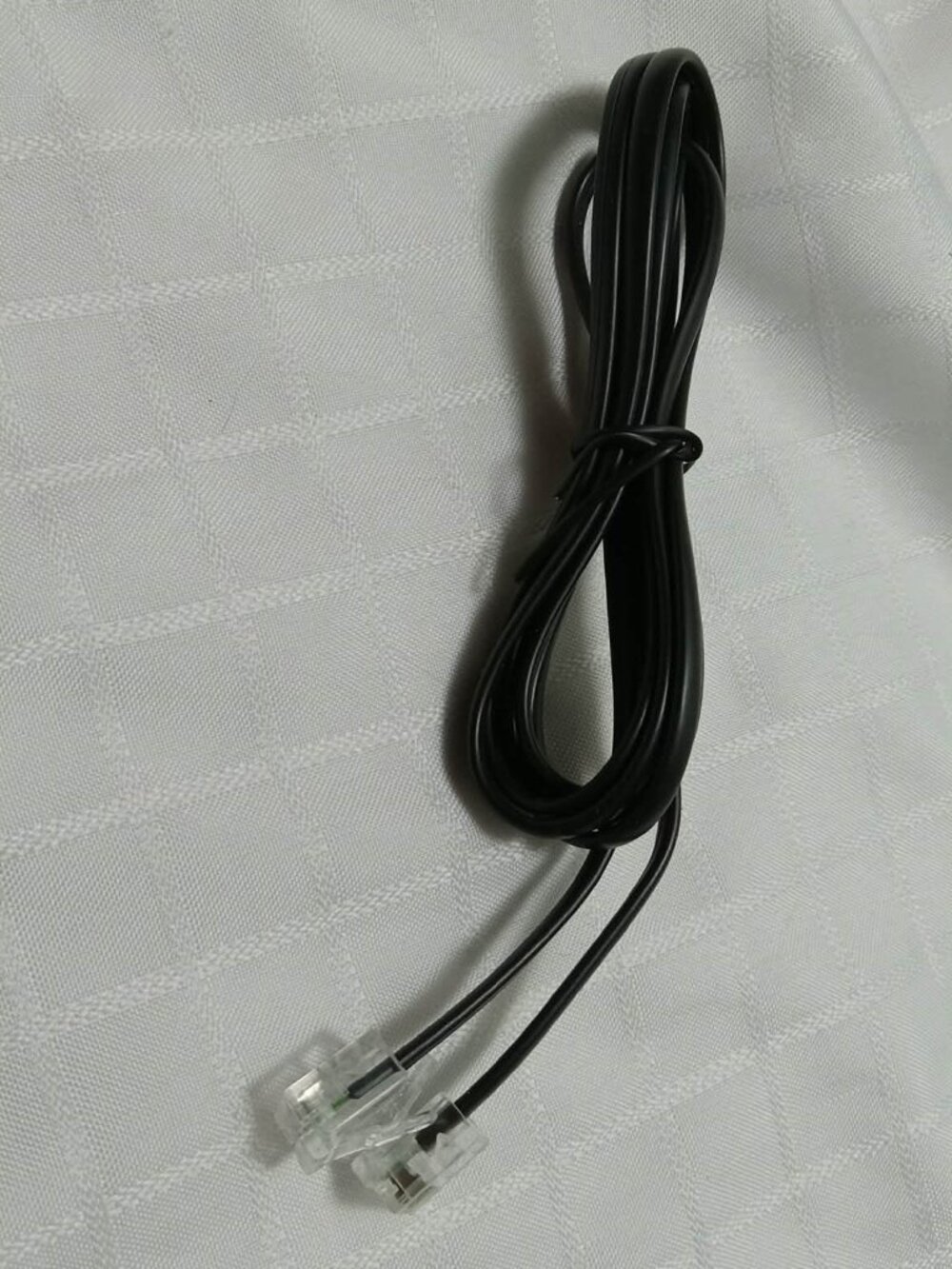 Black, flat telephone cable with 2 transparent RJ11 or RJ12 modular connectors
